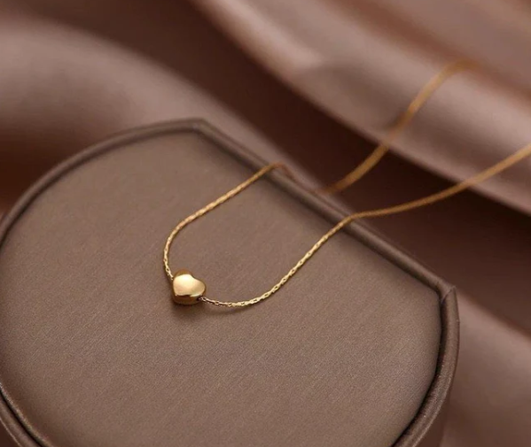 Gold necklace with a heart pendant on a brown surface